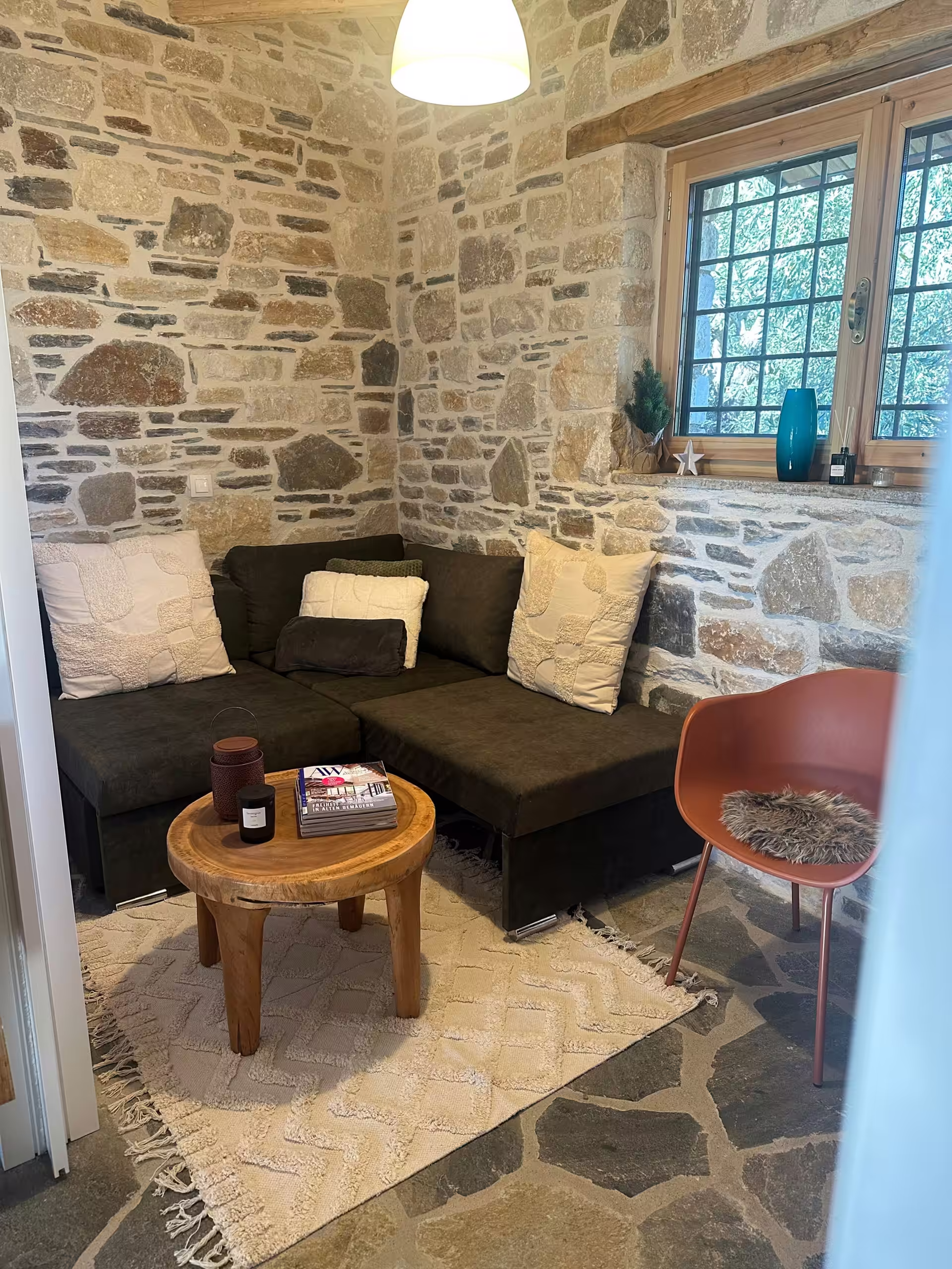 Sitzecke mit Sofa und Holztisch vor der Natursteinwand