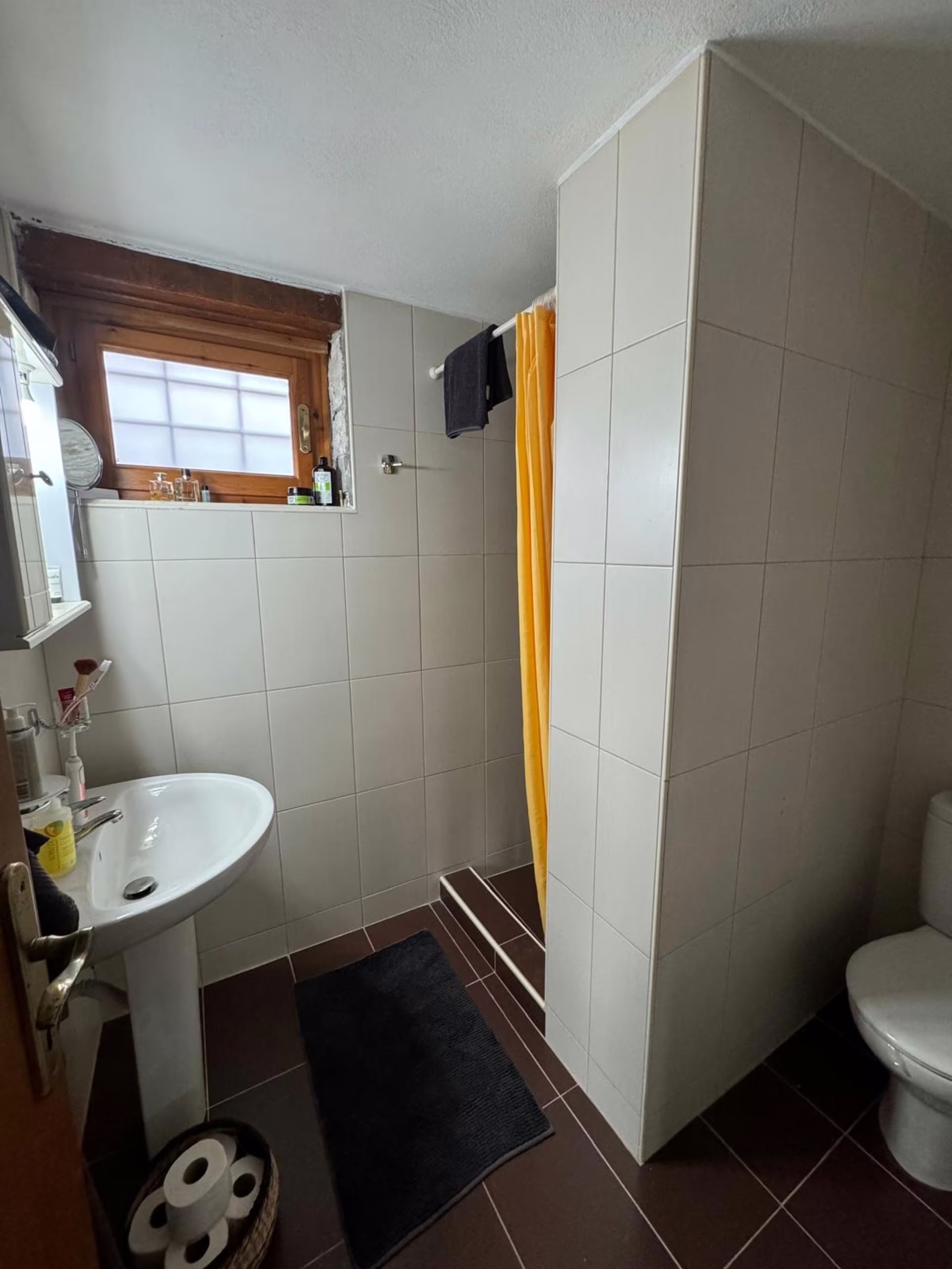 Bad mit Waschbecken, Fenster und Duschbereich