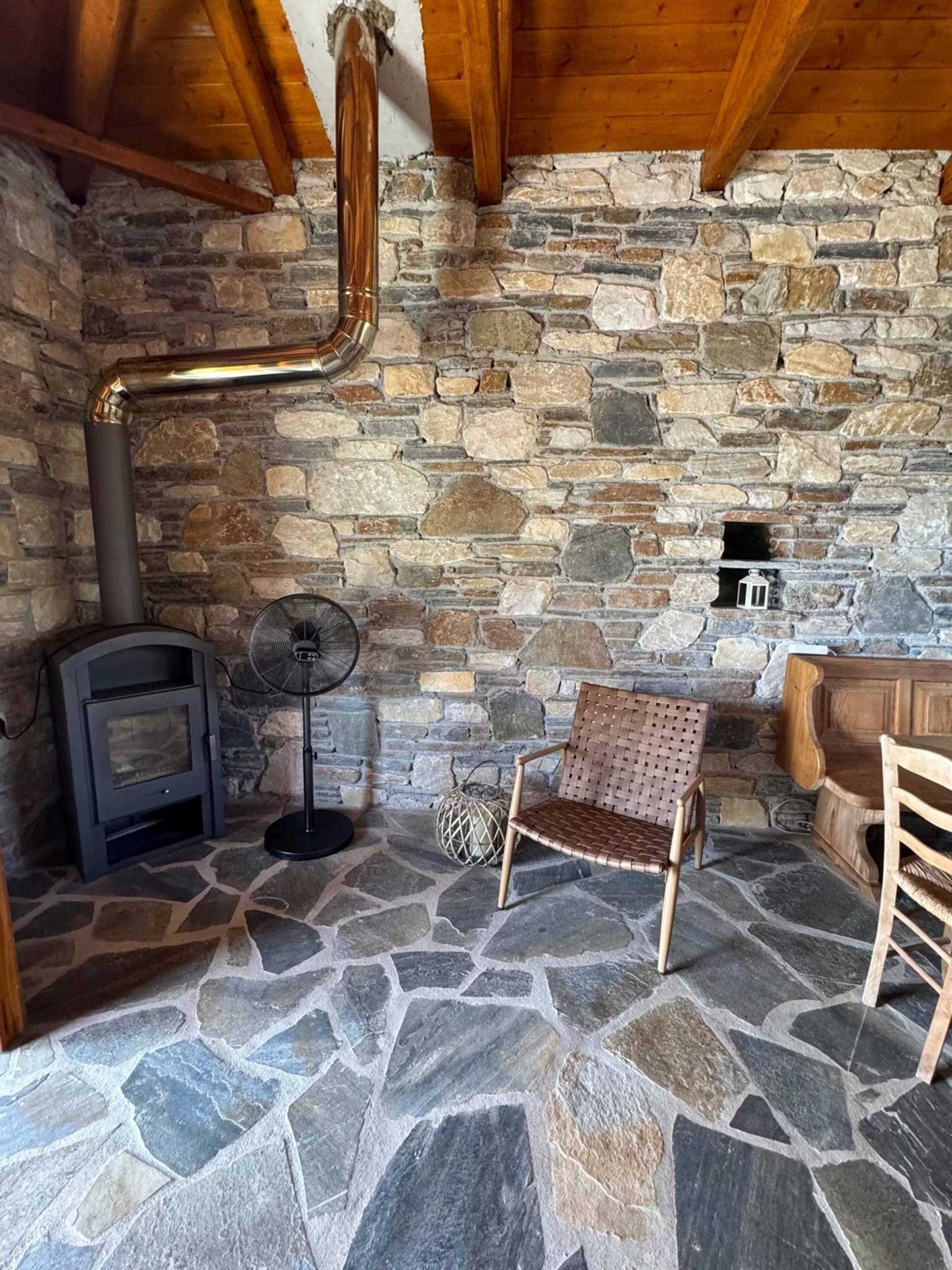 Wohnraum mit Natursteinwand und Holzofen