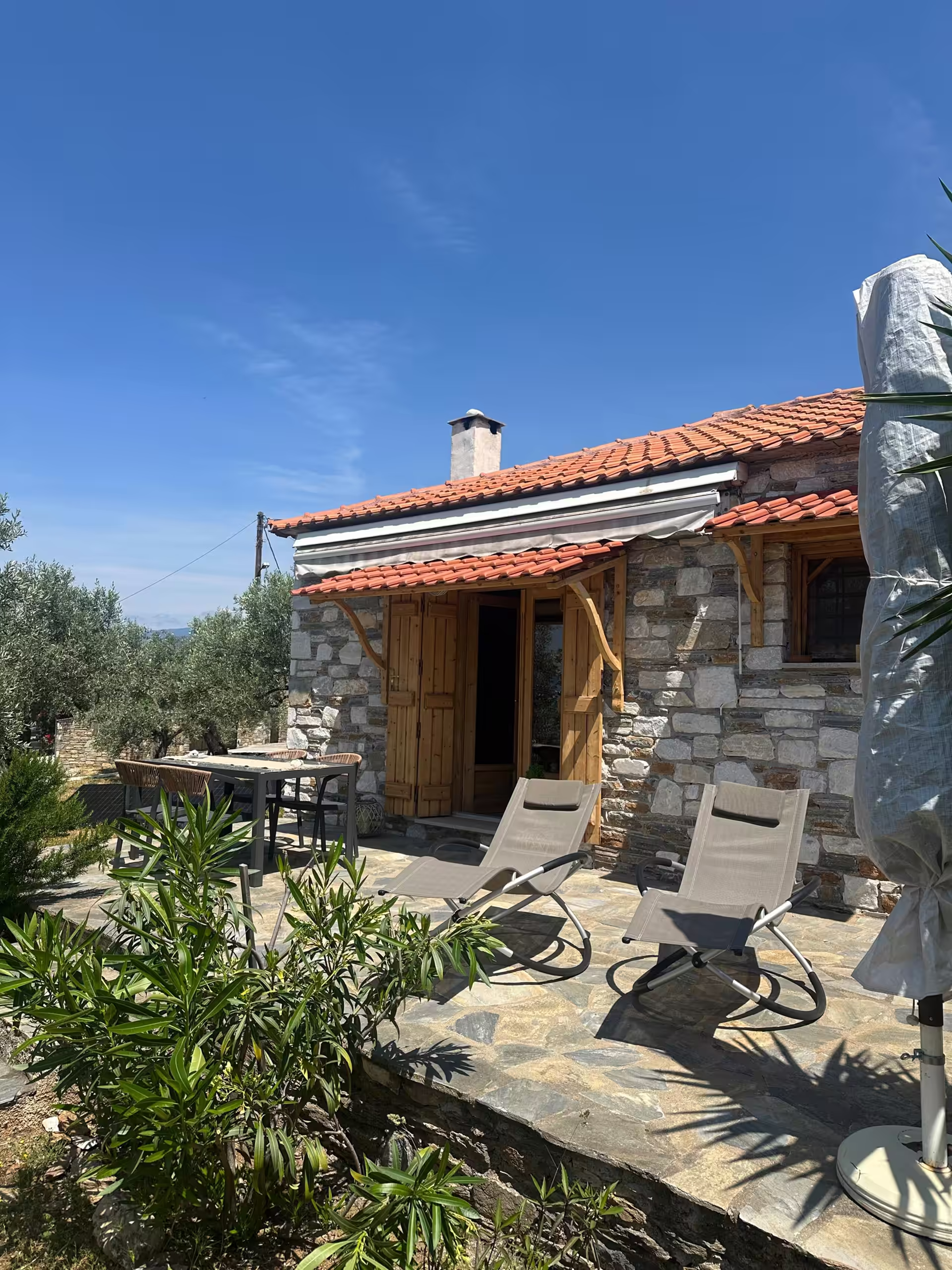 Das Steinhaus mit Ziegeldach, davor die Terrasse mit zwei Liegen