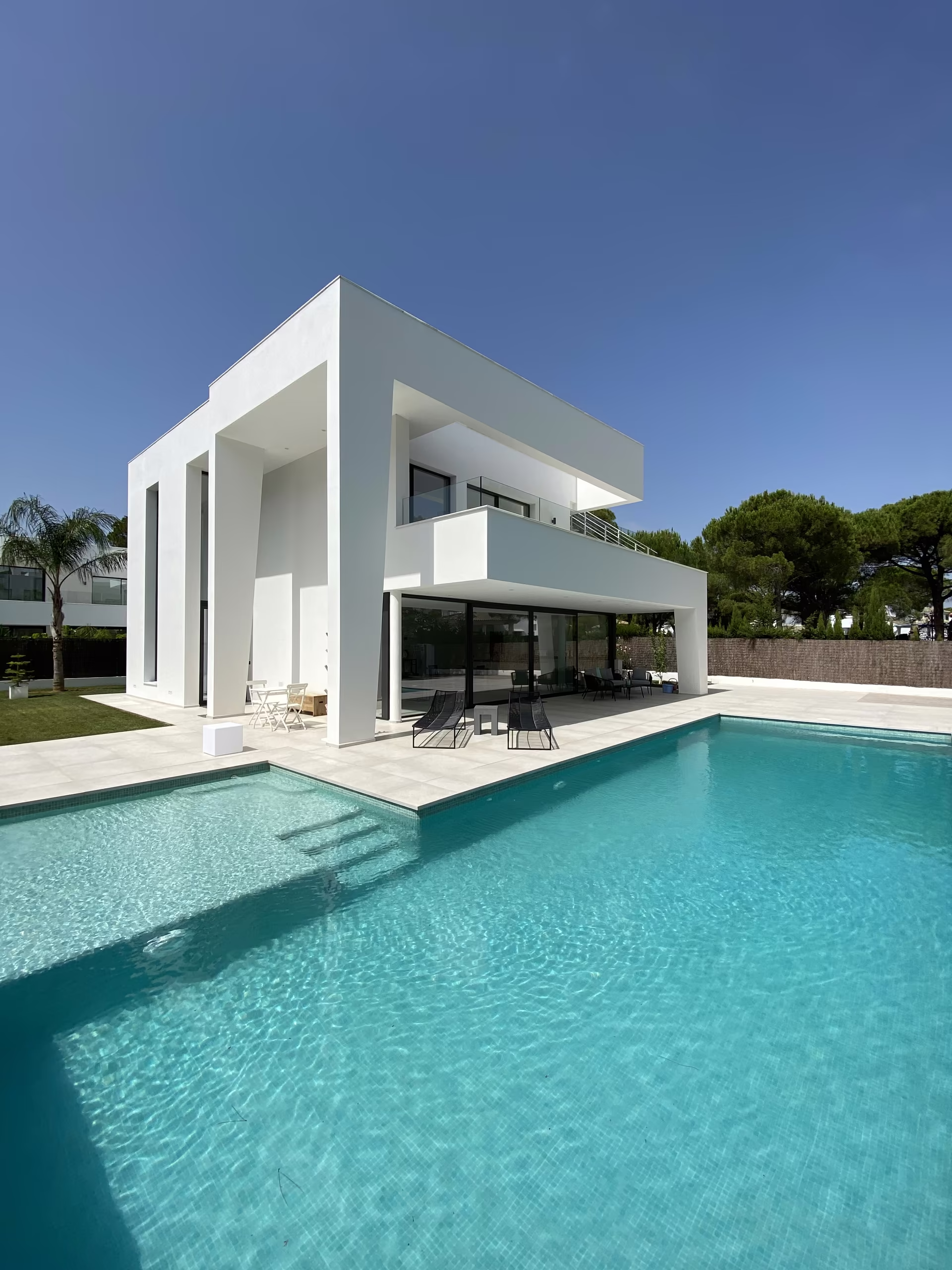 Die wei&szlig;e Villa mit ihrem langen Pool unter blauem Himmel