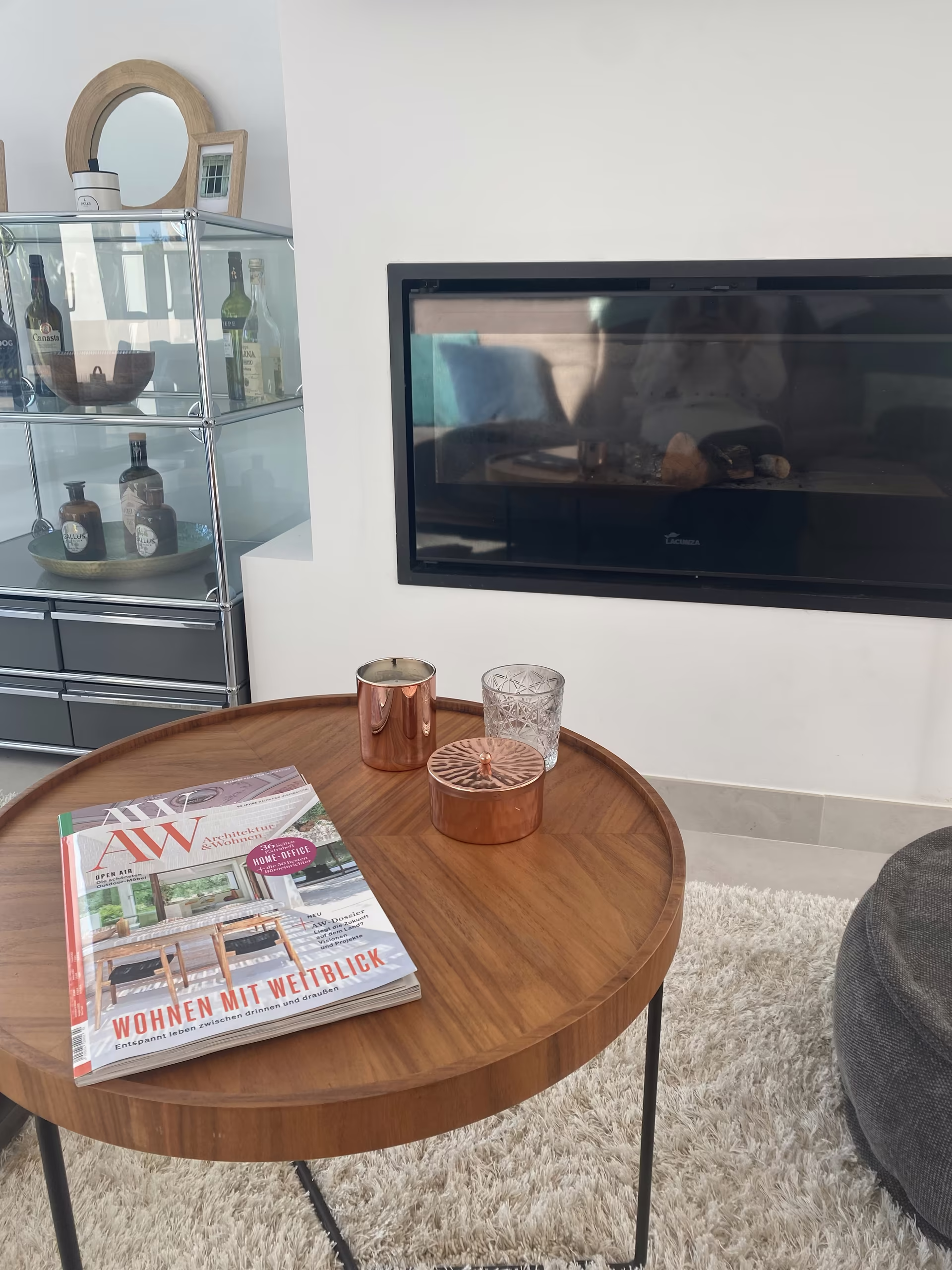 Runder Beistelltisch mit Kerzen und Zeitschrift vor dem Kamin