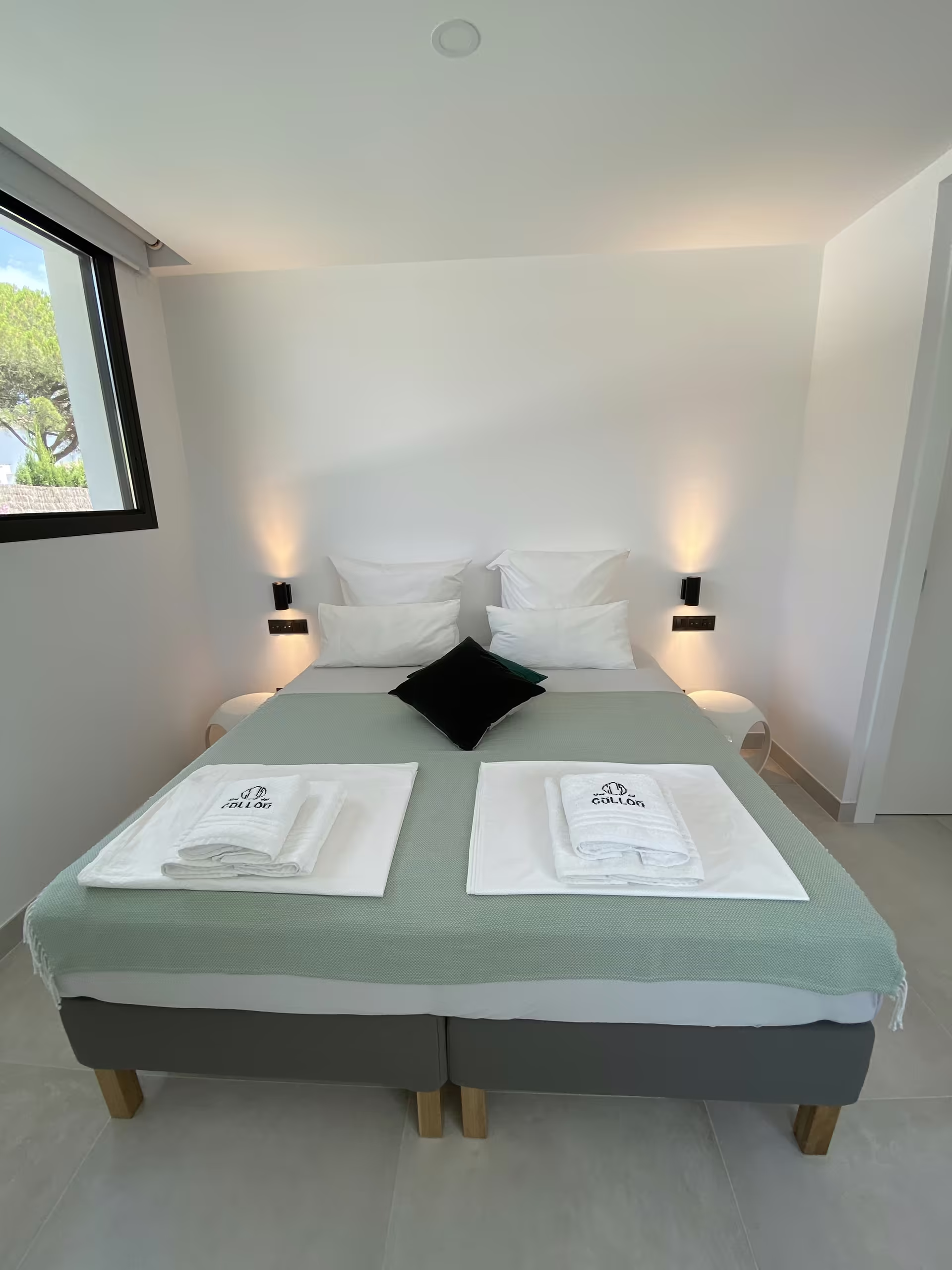 Schlafzimmer mit mintgr&uuml;ner Tagesdecke und Leselampen am Kopfende