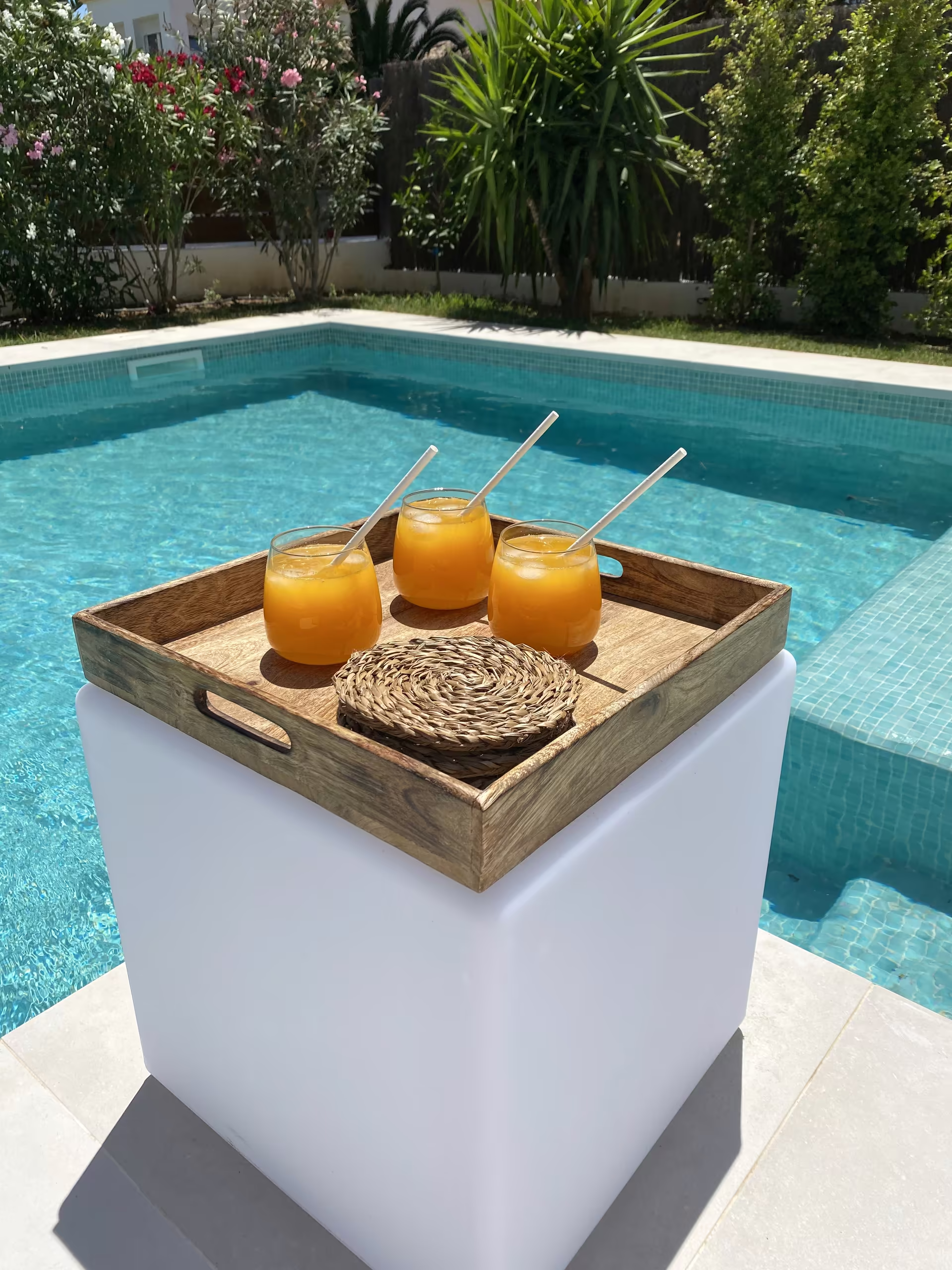 Zwei Gl&auml;ser Orangensaft auf einem Tablett am Pool