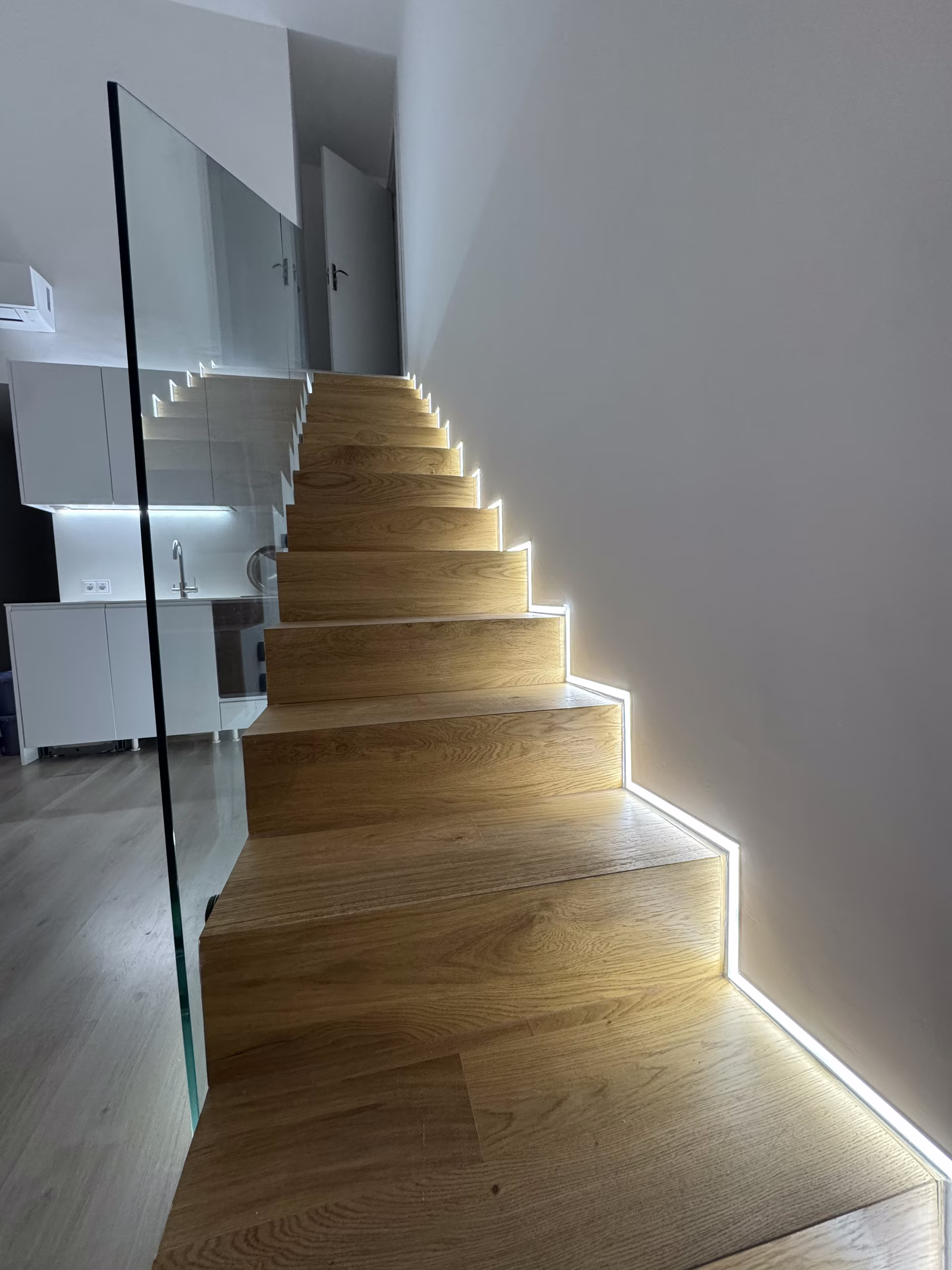 Holztreppe mit Glasgel&auml;nder, in jede Stufe ist ein Lichtband eingelassen