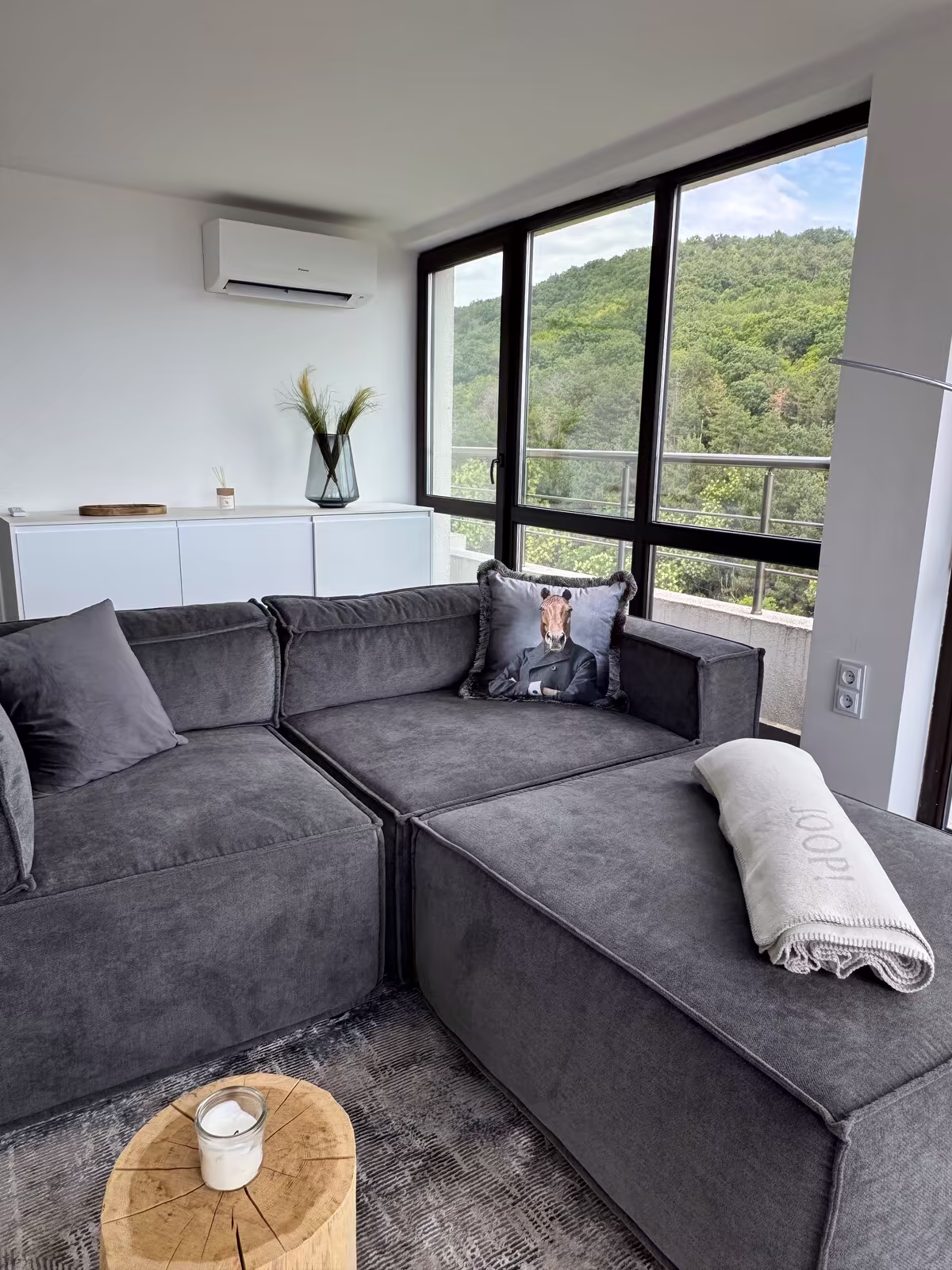Graues Ecksofa mit Kissen neben dem Fenster